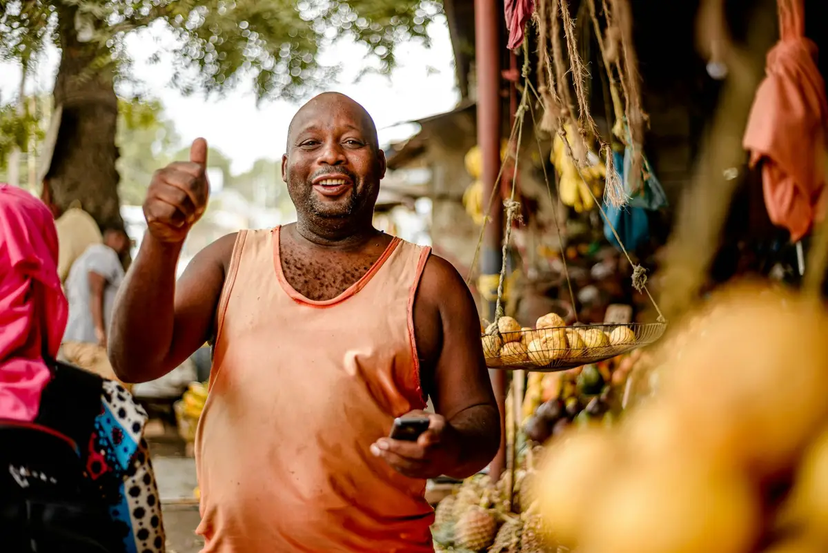 Un vendeur de fruits lève le pouce, son téléphone à la main